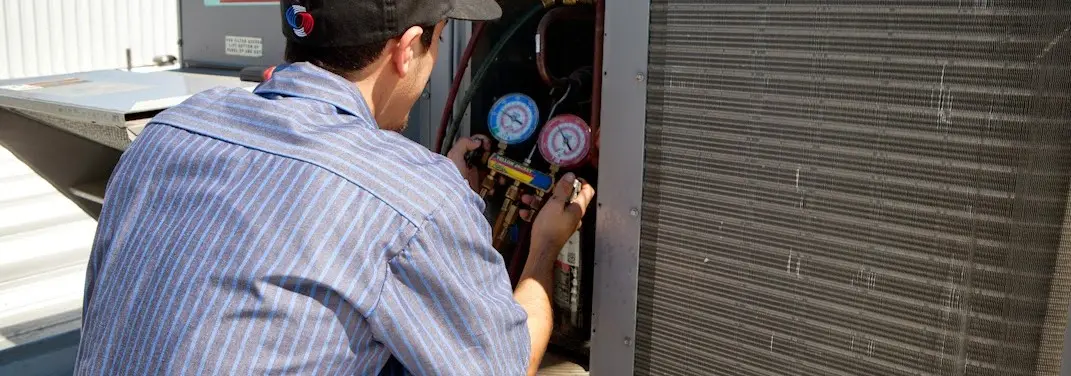 HVAC technician servicing a condenser unit in Fruita